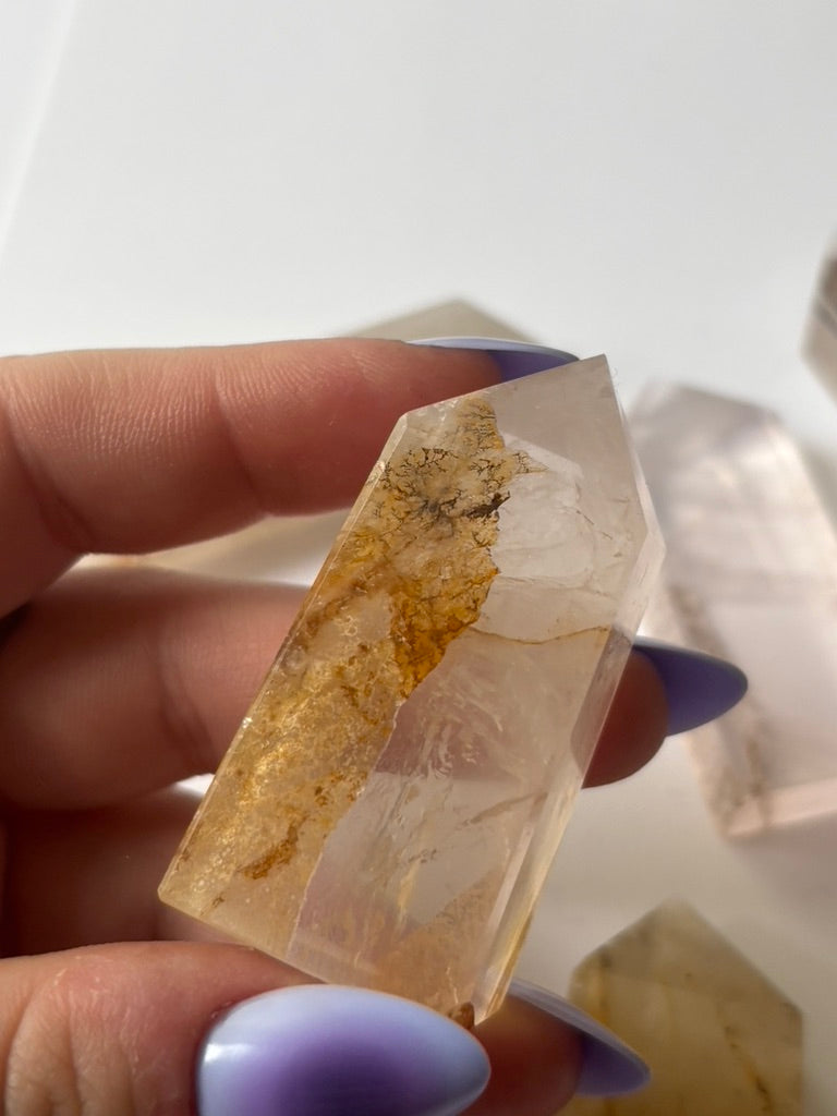 Hand holding a Golden Healer Dendritic Quartz tower to show size and detail — a powerful crystal for chakra alignment and energetic healing.