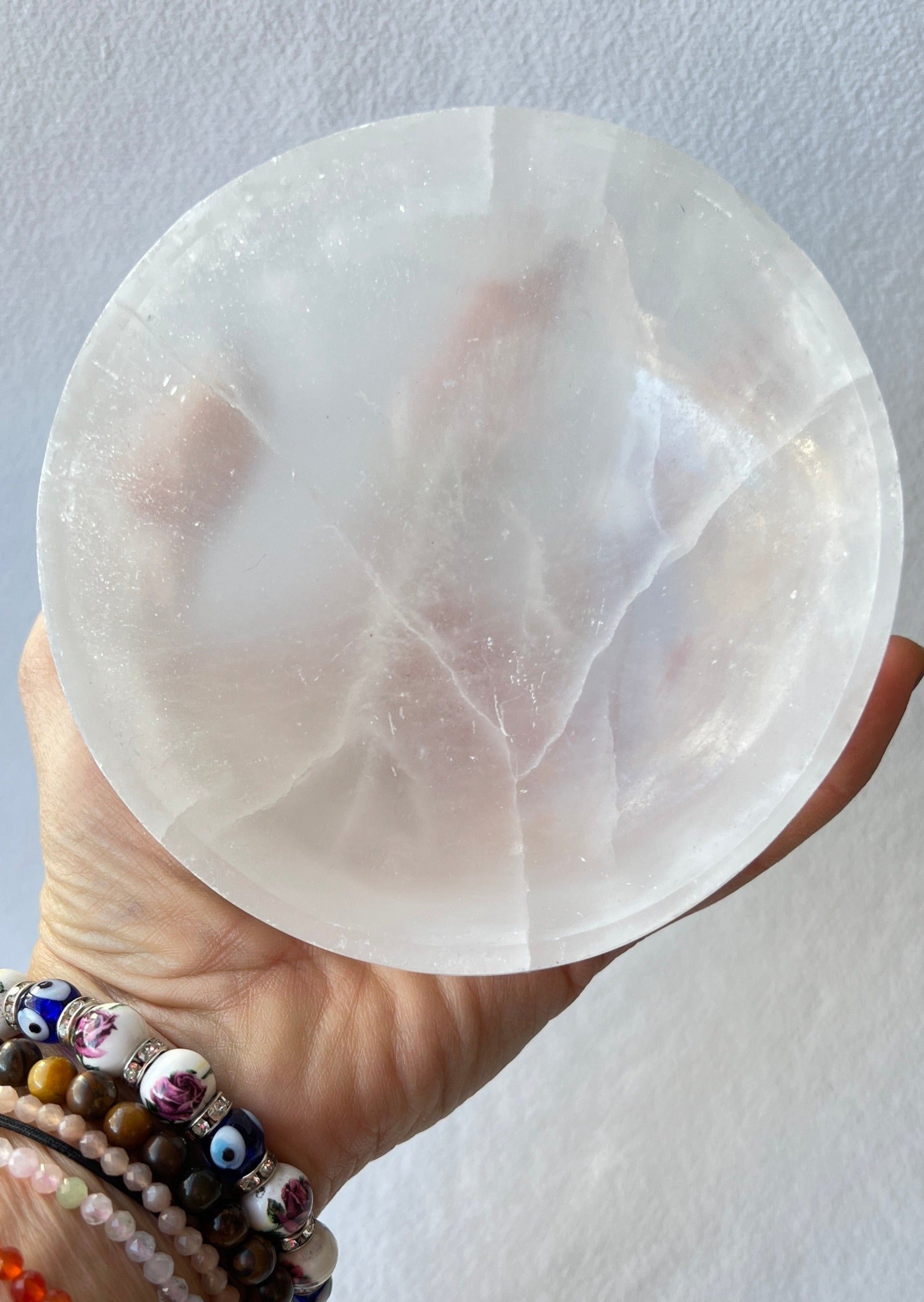White selenite charging bowl filled with healing crystals