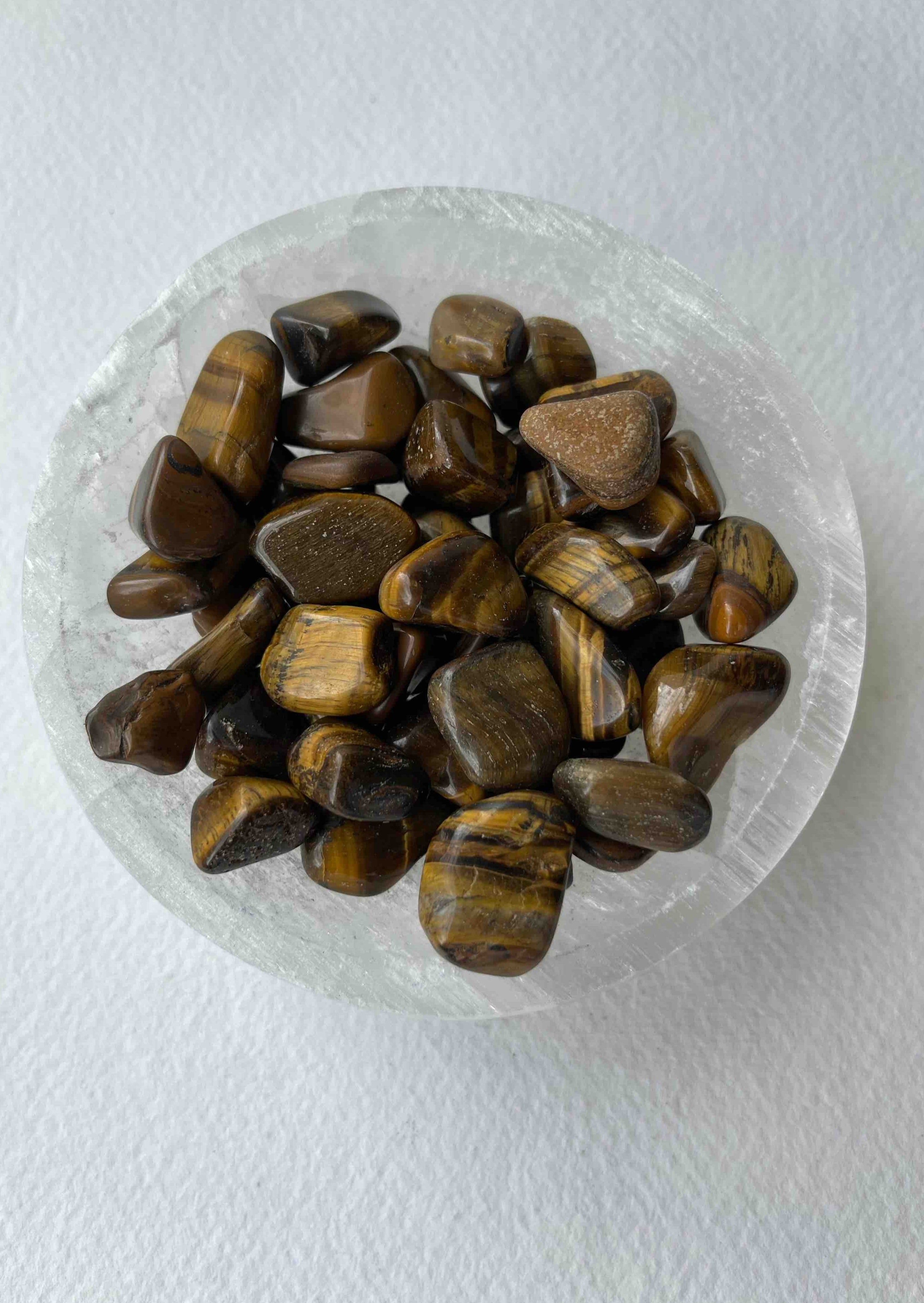 Tumbled Tiger’s Eye crystal with golden and brown chatoyant bands, known for grounding, protection, and boosting confidence.