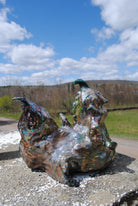 Metallic sculpture on a concrete surface with a scenic background