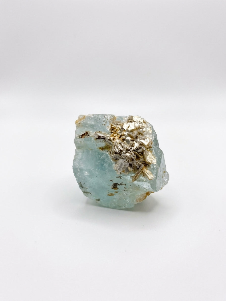 light blue aquamarine stone with golden lepidolite inclusions on one side 
