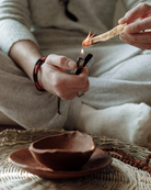 A lit Palo Santo stick burning with soft smoke, used in energy clearing and spiritual ceremonies.