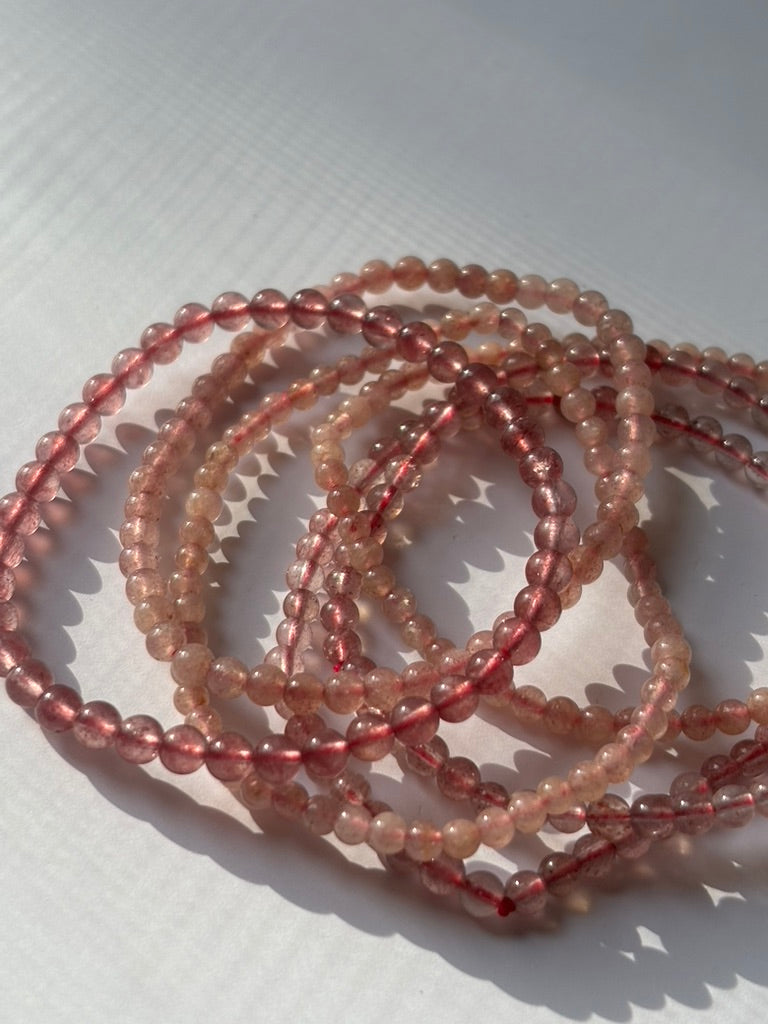 Close-up of crystal healing bracelets showing detailed gemstone strawberry quartz
